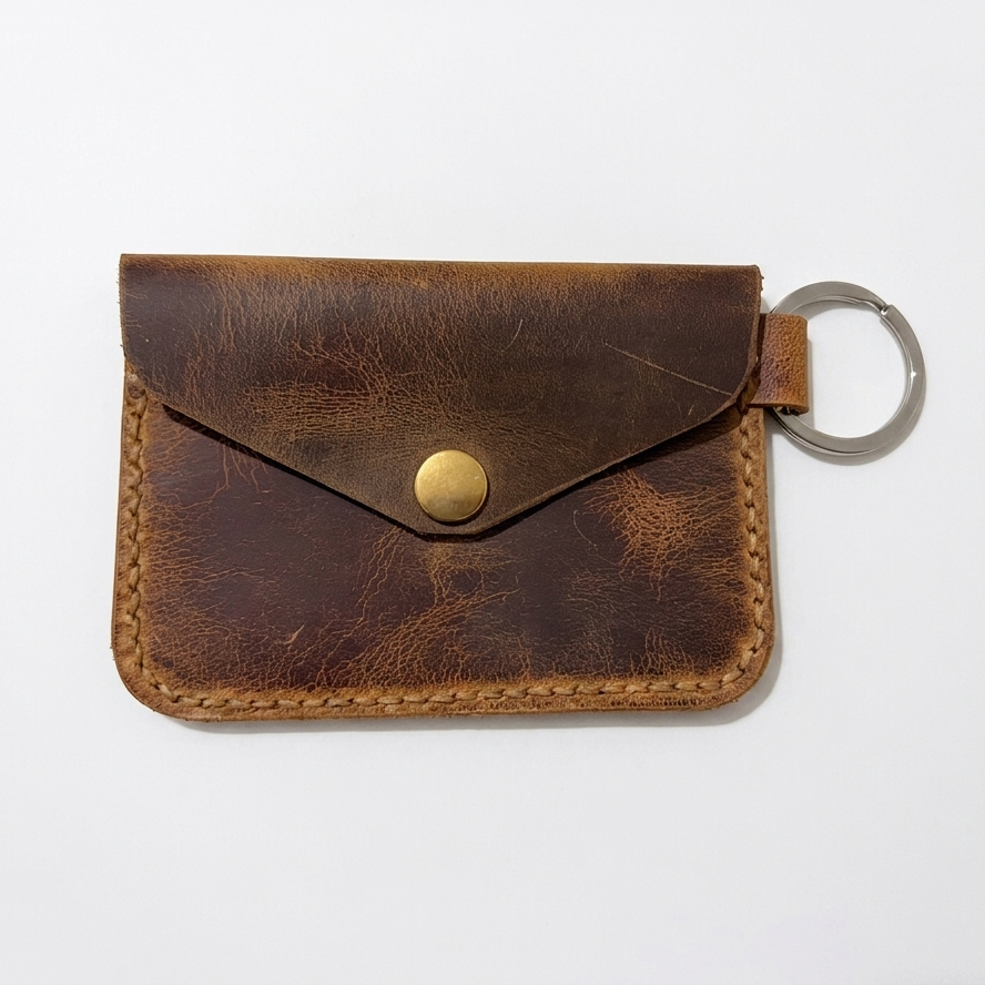 Brown leather cardholder with a key ring on a white background. AERA Berlin